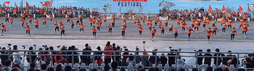 Cry of Jelicuon performers raising red flags and swelling into larger motion across the line